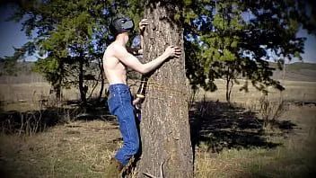 play Un jovencito cachondo con una máscara oscura se folla un juguete sexual que está atado a un árbol en un desierto público.